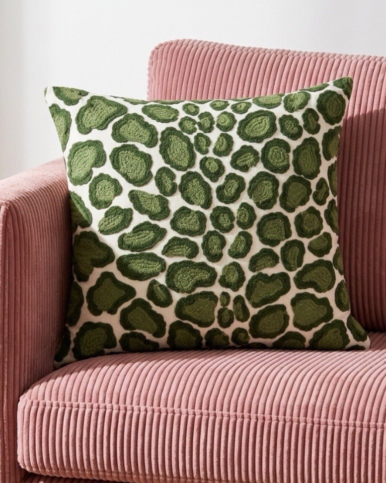 Coussin 50x50cm brodé vert Thevenon Coup de Griffe posé sur un fauteuil en velours côtelé rose